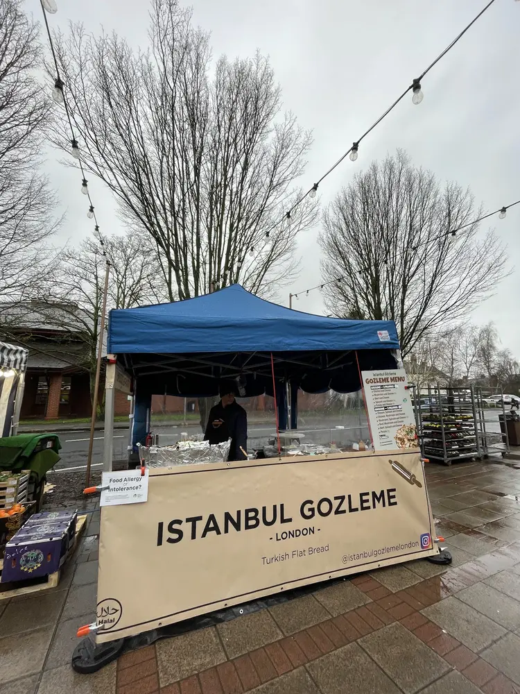 Istanbul Gozleme London stall with blue gazebo and beige banner on a wet market street